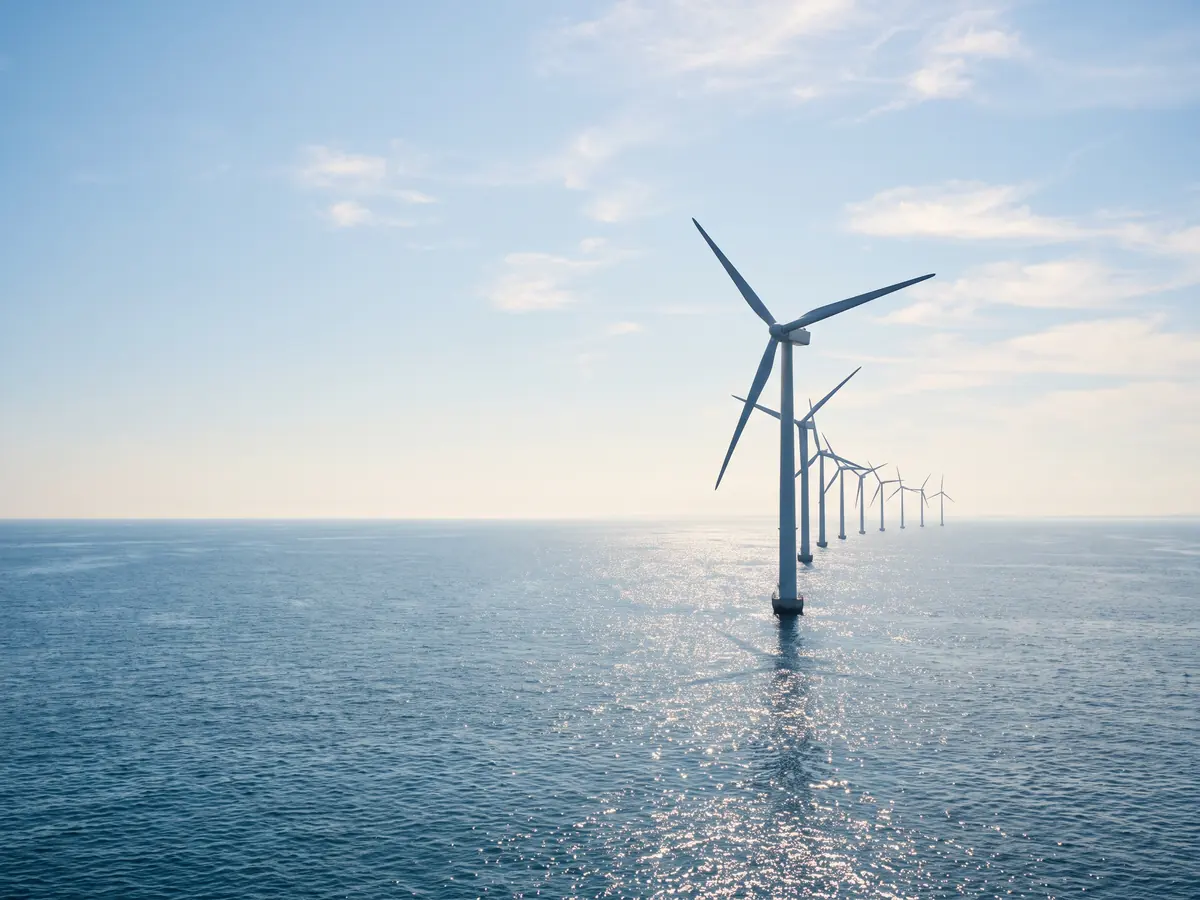 A generated photograph of offshore wind turbines standing in a calm, sunlit blue sea